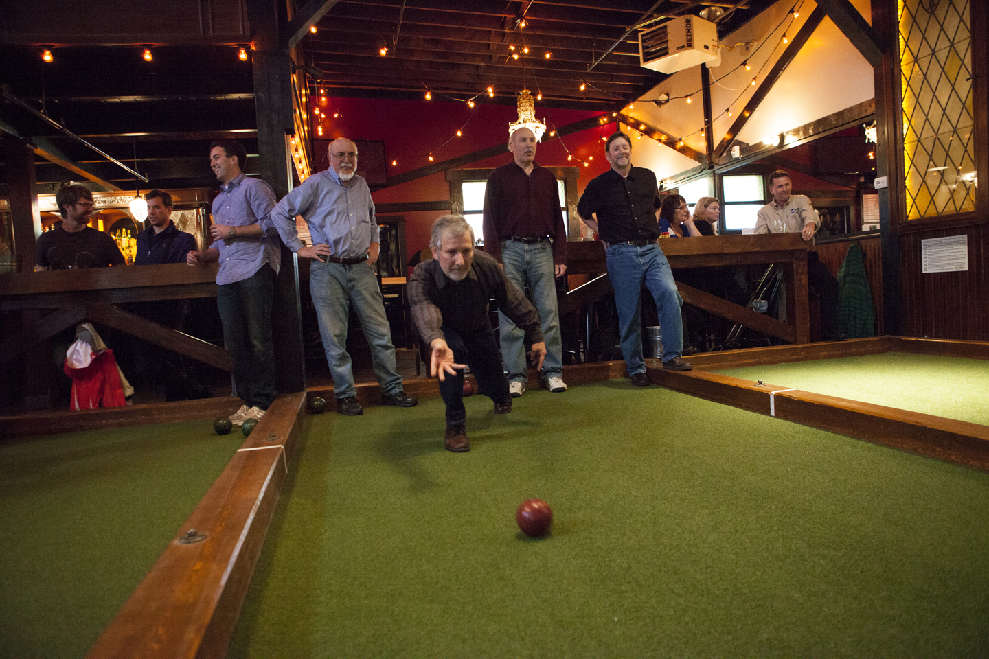 Greg Singleton goes for a knockout on one of Von Trapp’s many bocce courts. After the game, he and his friends can dine on a menu that includes, from top right, pretzels, beets, and sliders.