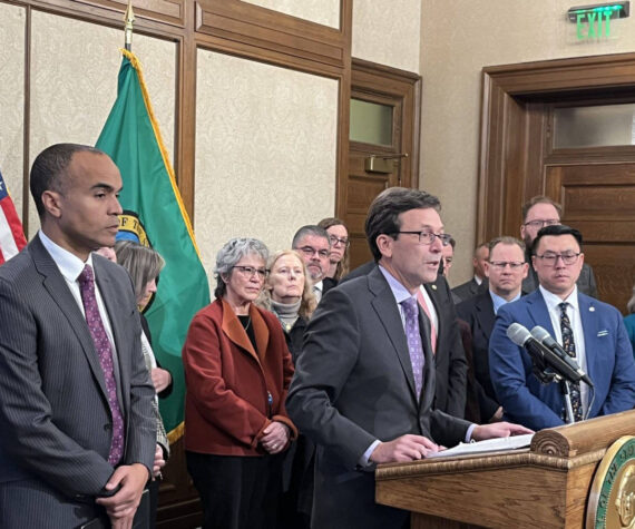 Gov. Bob Ferguson, surrounded by other state elected leaders, speaks at a Feb. 13 press conference in Olympia. (Photo by Bill Lucia/Washington State Standard)